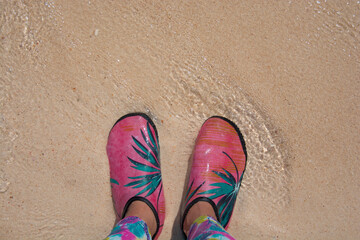 Fototapeta premium Woman standing on the beach sand and wearing wading shoes, beach of Krabi, Thailand