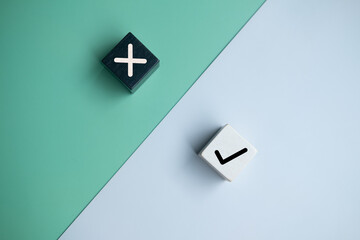 True and false symbols accept rejected on wood cubes for evaluation on a two colored background.