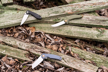 Several different pocket knives. Pocket knives on a wooden background. Knives of various shapes.