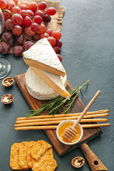 Tasty cheese and snacks on dark background