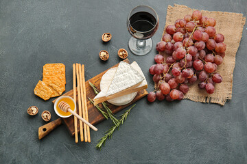 Glass of wine, cheese and snacks on dark background