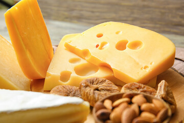 Tasty cheese, nuts and dried figs on wooden background, closeup