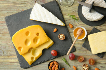 Tasty cheese, honey, nuts and grapes on wooden background