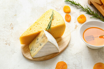 Tasty cheese, dried apricots and honey on light background, closeup