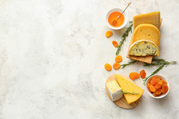 Different types of cheese, dried apricots and honey on light background