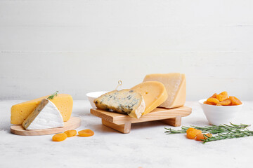 Different types of cheese and dried apricots on light background