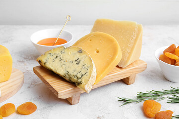 Different types of cheese, dried apricots and honey on light background, closeup