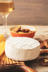 Fototapeta na wymiar Tasty cheese, wine and nuts on wooden background, closeup