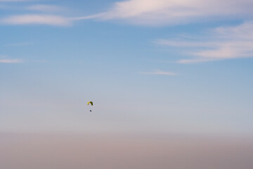 Paraglider silhouette flying on blue sky background. Nature landscape. Concept: adventure, art, travel. Blue sky background. Ushkonyr plateau, Kazakhstan. Travel in Kazakhstan concept.