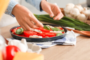 Young woman cooking tasty pizza in kitchen
