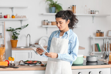 Young woman using tablet computer in kitchen