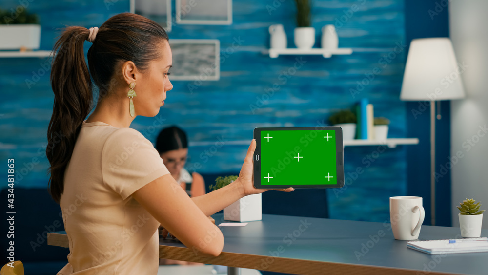 Poster woman looking at tablet computer with mock up green screen chroma key display browsing on internet s