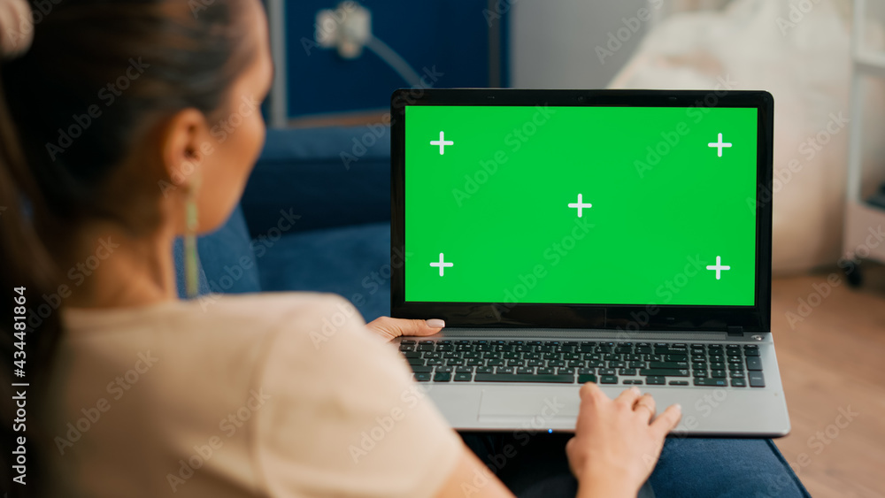 Poster close up of freelencer using laptop computer with mock up green screen chroma key display while sitt