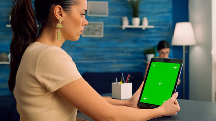Freelancer holding tablet computer with mock up green screen chroma key display during virtual...