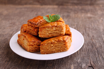 Baklava, traditional Turkish dessert. Crispy baklava on white plate, on a old wooden background.
