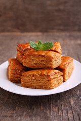 Baklava, traditional Turkish dessert. Crispy baklava on white plate, on a old wooden background.