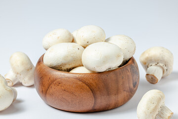 Fresh white champignons in brown bowl on white background.