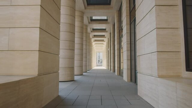 Walkthrough between colonnade and modern office building in city downtown