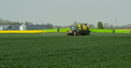 Fototapeta na wymiar Traktor mit Feldspritze beim Ausbringen von Pflanzenschutzmittel gegen Pestizid