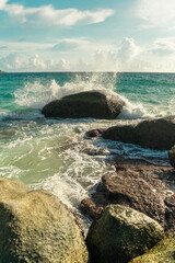 Coral stones and sea waves hitting the rocks on sunset lights. Vertical photo