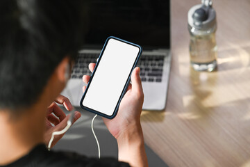 Sportsman wearing earphones and using smart phone preparing for exercising at home.