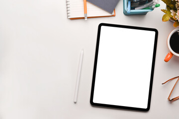 Designer workspace with digital tablet, coffee cup, notebook and stationery on white table.