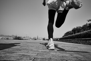 close-up shot of legs and feet of a young asian woman running outdoors, black and white