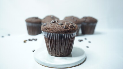Selective background of homemade chocolate muffin on a white ceramic plate with some blur muffin at behind as a background