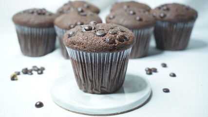 Selective focus of homemade chocolate muffin on mini ceramic plate and with some chocolate muffin behind as a background