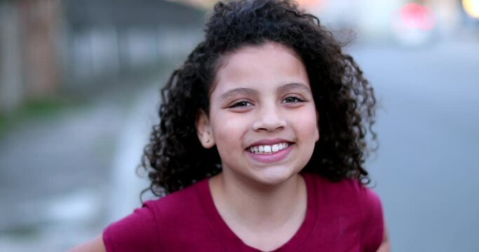 Little child girl smiling at camera. Hispanic female kid portrait face close-up