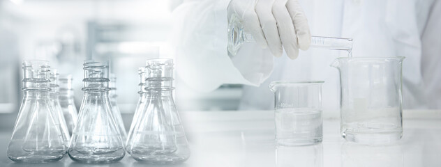 scientist in white coat poring water into glass beaker in medical laboratory science background