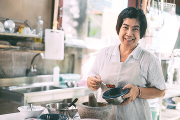 Authentic portrait asian elderly woman cooking local traditional thai style food.
