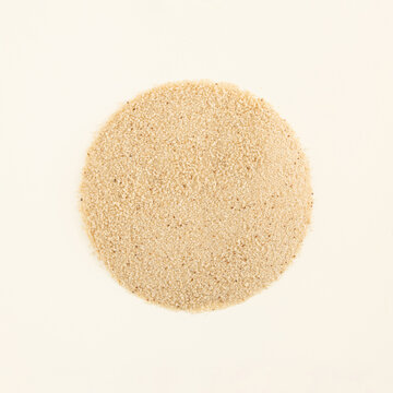 Sandy texture circle made of African ancient cereal fonio millet gluten free whole grain on a pastel beige background. Minimal organic natural healthy food flat lay concept with copy space.