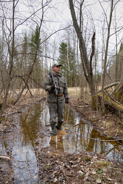 a hunter wades through a puddle on a forest road