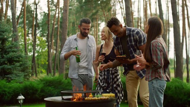 Multiracial friends having chat on backyard. Man cooking vegetables on bbq grill