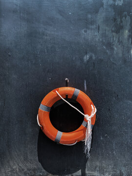 Orange rescue lifebuoy on dark grey background. Minimal travel by sea background