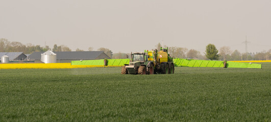 Traktor mit Feldspritze beim Ausbringen von Pflanzenschutzmittel gegen Pestizid