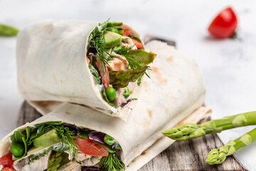 tortilla wraps chicken and vegetables asparagus, avocado, tomatoes, peas, cheese on cutting board. Food recipe background. Close up