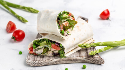 Tortilla wrap with chicken meat and vegetables asparagus, avocado, tomatoes, peas, cheese and...