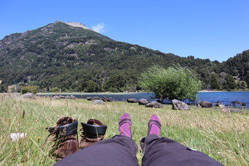 Having a break after a long hike, trekking through valleys, volcanoes and rivers in the Lanin National Park Patagonia Argentina South America, feet and shoes over a meadow on a sunny day