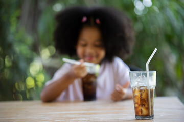 childhood and eating concept - little african american curly hair girl drinking soft drinks.