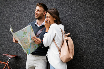 Holidays, dating and tourism concept. Smiling couple in love with map in the city