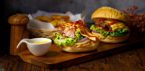 Homemade hamburger with sauce and bacon on top in dark style light