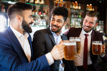 People, friendship and celebration concept. Happy business male friends drinking beer at pub