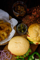 Ready to eat homemade hamburger with glass of drink in background. Taken with dark style light