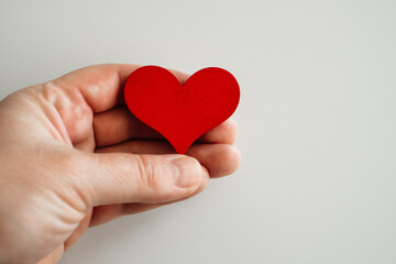 wooden red heart in hand, on a white background