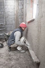 Real construction worker working on a wall inside the new house.