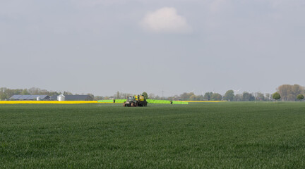 Traktor mit Feldspritze beim Ausbringen von Pflanzenschutzmittel gegen Pestizid
