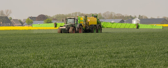 Traktor mit Feldspritze beim Ausbringen von Pflanzenschutzmittel gegen Pestizid
