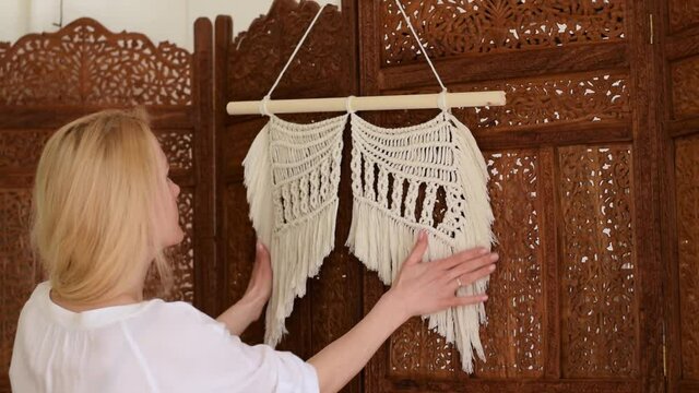 Attractive blonde woman demonstrates home decor made in the macrame technique.Slow motion.